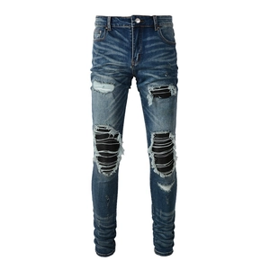 Détail du jean denim avec déchirures usées et empiècements à rayures horizontales noires