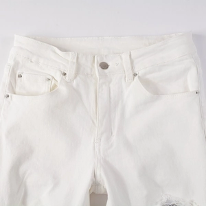 Detail of waist and button fly on white distressed jeans with sequin patch accents