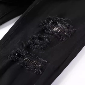 Slim fit black distressed denim jeans with rhinestone accents and frayed holes