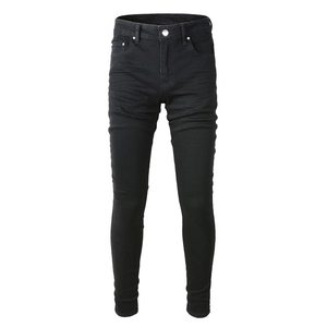 Vue détaillée du jean noir slim fit montrant le bouton en métal et les moustaches