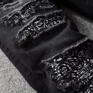 Men's black ripped jeans with stylish paisley pattern patches in street style