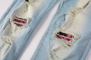 Close-up of ripped denim jeans with unique red paisley fabric patch under the distressed hole