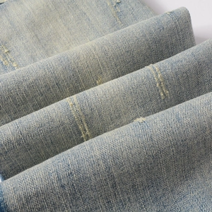 Detailed view of light blue vintage washed denim with distressed ripped and worn textures