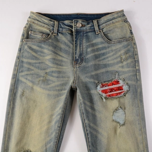Detail of distressed jeans with red bandana patch and vintage washed texture