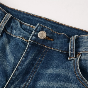 Détail de la taille d'un jean en denim foncé avec bouton métallique et coutures jaunes