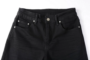 Détail de la taille d'un jean noir avec bouton argenté et poche monnaie en gros plan