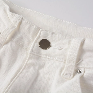 Close-up of waistband on white stretch denim jeans with metal button and rivet details
