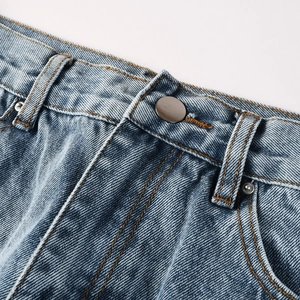 Detail of light blue denim jeans waist with metal button, orange stitching and rivets