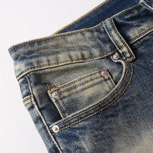 Close-up of slim-fit denim jeans with vintage wash effect and metal rivet pockets