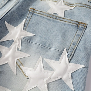 Detail of light blue denim rear pocket with white faux leather star patches and stitching