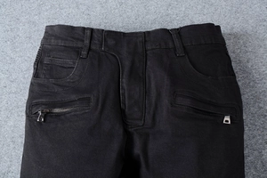 Dettaglio dei jeans biker neri slim fit con tasche a zip metalliche e trama denim pesante
