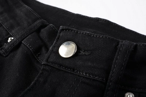 Gros plan détaillé du bouton en métal argenté et des coutures renforcées du jean denim noir