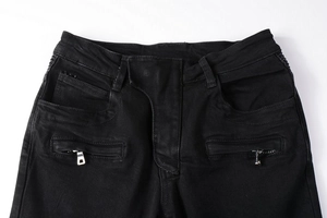 Detail view of black biker jeans showing dual silver metal zippers and waist stitching
