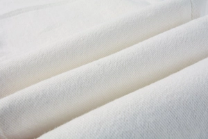 Close-up of white slim-fit trousers showing soft cotton fabric texture and premium weaving