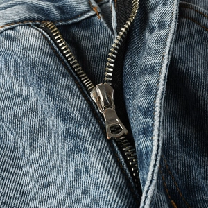 Detail shot of the metal zipper and washed denim texture on blue flare jeans