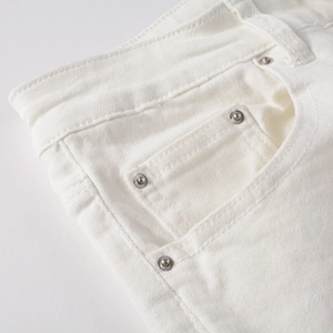 Macro view of pocket stitching and silver rivets on white ripped stretch jeans
