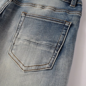 Detail of light blue washed denim back pocket with vintage stitching and worn texture