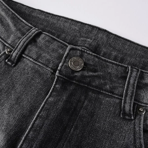 Détails du bouton métallique et de la braguette sur un jean noir évasé pour hommes
