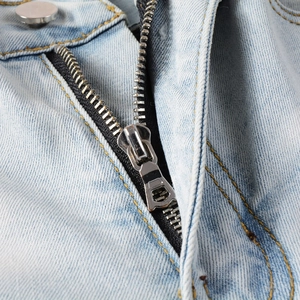Vue macro détaillée d'un jean bleu clair avec bouton argenté et braguette zippée