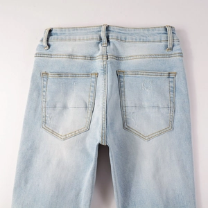 Détail des poches arrière délavées sur un jean denim bleu clair déchiré pour homme