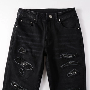 Detail of street style black ripped jeans showing paisley pattern patches and denim texture