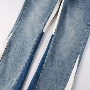 Detailed close-up of side color-block design on men's flare light blue washed jeans