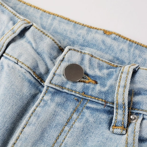Détail de la taille en denim bleu clair avec coutures jaunes et bouton métallique