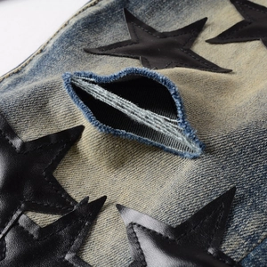Close-up of vintage blue washed jeans featuring leather star patches and distressed details