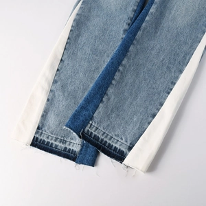 Close-up of denim jeans hem featuring side stripes and raw-cut distressed edges