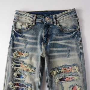 Détail de jean déchiré délavé vintage avec des patchs intérieurs à motifs paisley