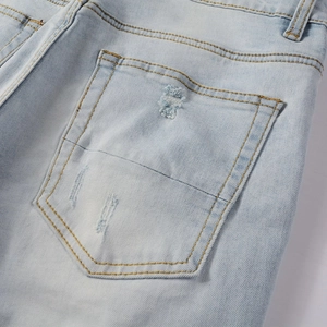 Détail de la poche arrière de jean bleu clair avec doubles coutures jaunes et usure