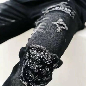 Men's slim black ripped jeans featuring paisley patches and white cross embroidery details