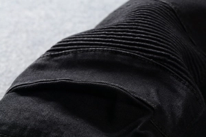 Dettaglio delle cuciture a coste sulle ginocchia e trama denim dei jeans biker neri