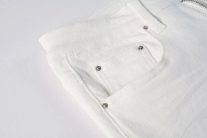 Detailed close-up of white denim jeans featuring silver metal rivets and twill fabric texture
