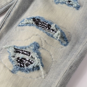 Detailed view of heavy distressed rips with camouflage patch lining on blue jeans