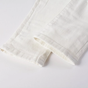 Close-up of white stretch denim pants leg showing premium stitching and twill texture