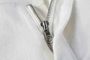 Detail shot of white denim fabric with a silver metal zipper and intricate texture
