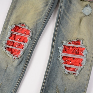 Men's blue distressed mud wash jeans with red paisley print lining at the ripped knee area
