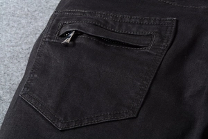 Dettaglio dei jeans moto neri con tasca a cerniera metallica e tessuto in twill di cotone