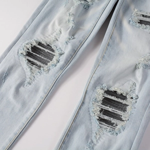 Détail d'un jean bleu clair usé avec déchirures et empiècements en tissu rayé chic