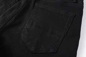 Détail du jean noir ajusté montrant les coutures de la poche arrière et la texture