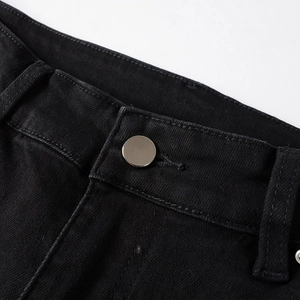 Macro view of black denim waist featuring a silver metal button and precise stitching