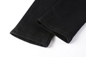 Gros plan de l'ourlet du jean noir montrant les détails de la double couture soignée