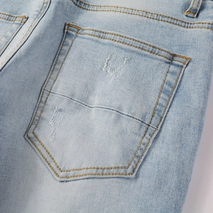 Détail du jean bleu clair délavé montrant la poche arrière avec coutures jaunes