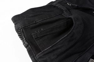 Dettaglio dei jeans biker neri che mostra l'elastico in vita e le cuciture delle tasche