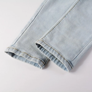 Détail de la couture d'ourlet renforcée sur un jean bleu délavé pour hommes