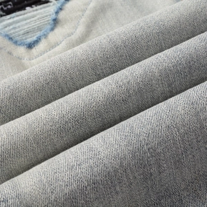 Detailed macro view of light blue distressed denim fabric with ripped texture and washed finish