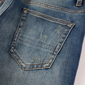 Gros plan de la poche arrière de jean bleu avec double couture et détails usés de style