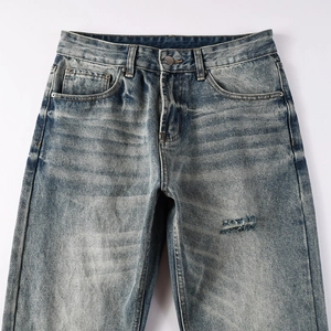 Détail du jean denim bleu vintage avec déchirures usées et surpiqûres contrastées pour homme