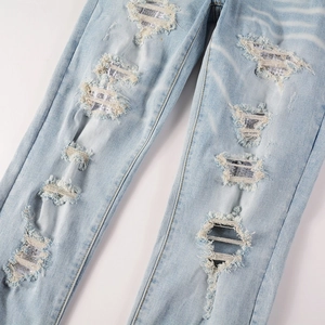 Détail de jean déchiré avec incrustation de résille en strass argentés et bords effilochés